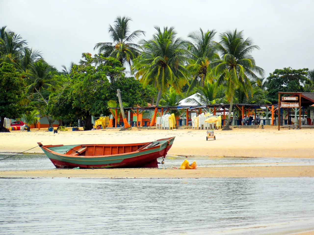 Barco colorido diante da praia e dos coqueiros de Coroa Vermelha.