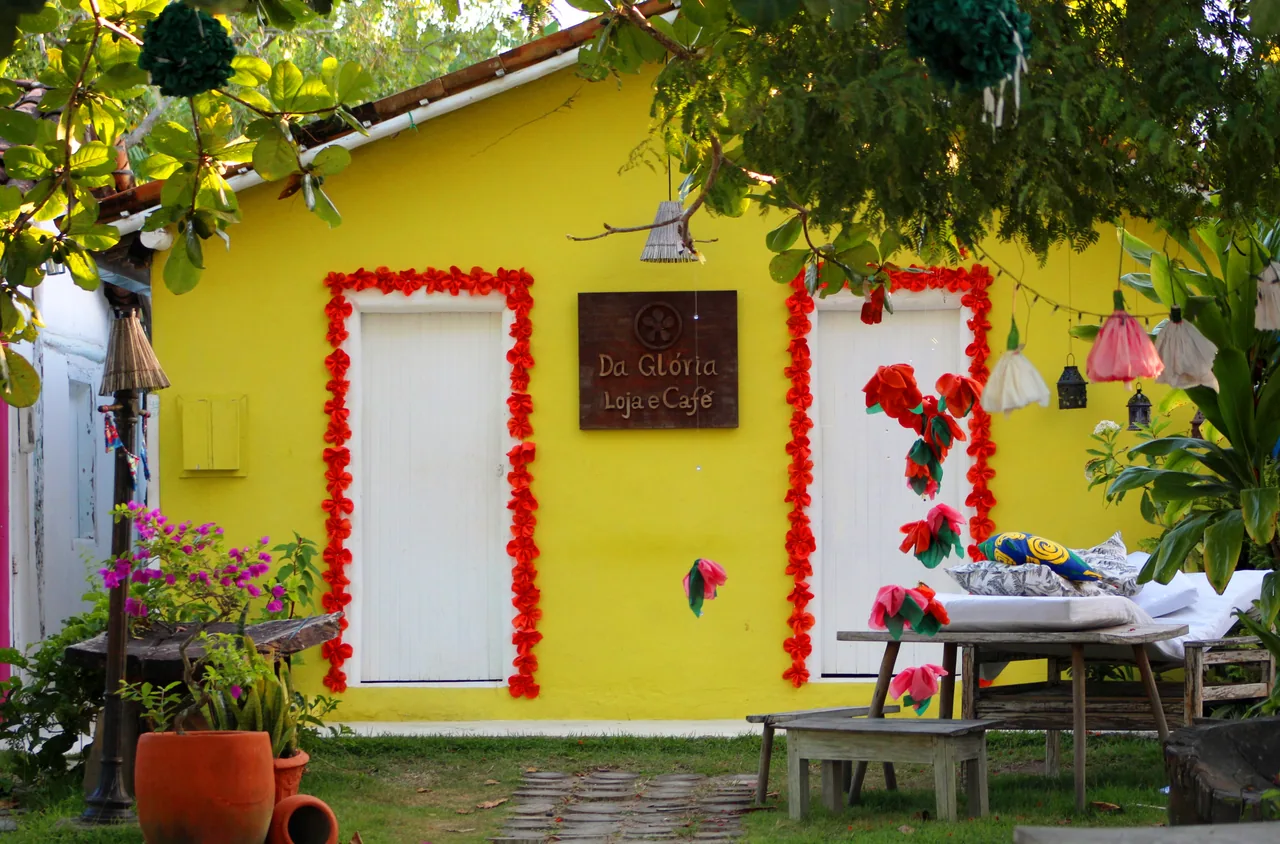 Casa amarela do Quadrado de Trancoso, com portas brancas e flores vermelhas.